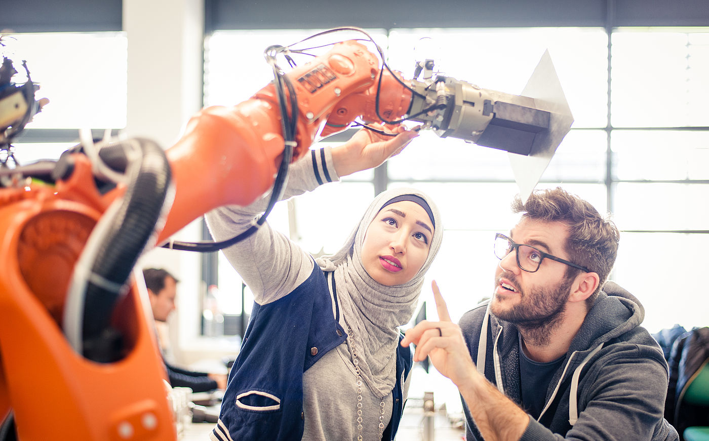 Zwei Studierende der HS Hannover arbeiten an einem großen Roboter 